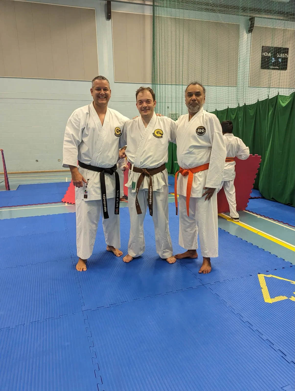 Three instructors in black, brown and orange belts posing together