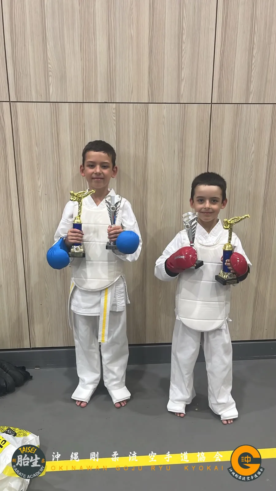 Two young students posing with their tournament trophies